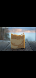 Bar of soap on a wooden surface with a blurred natural background