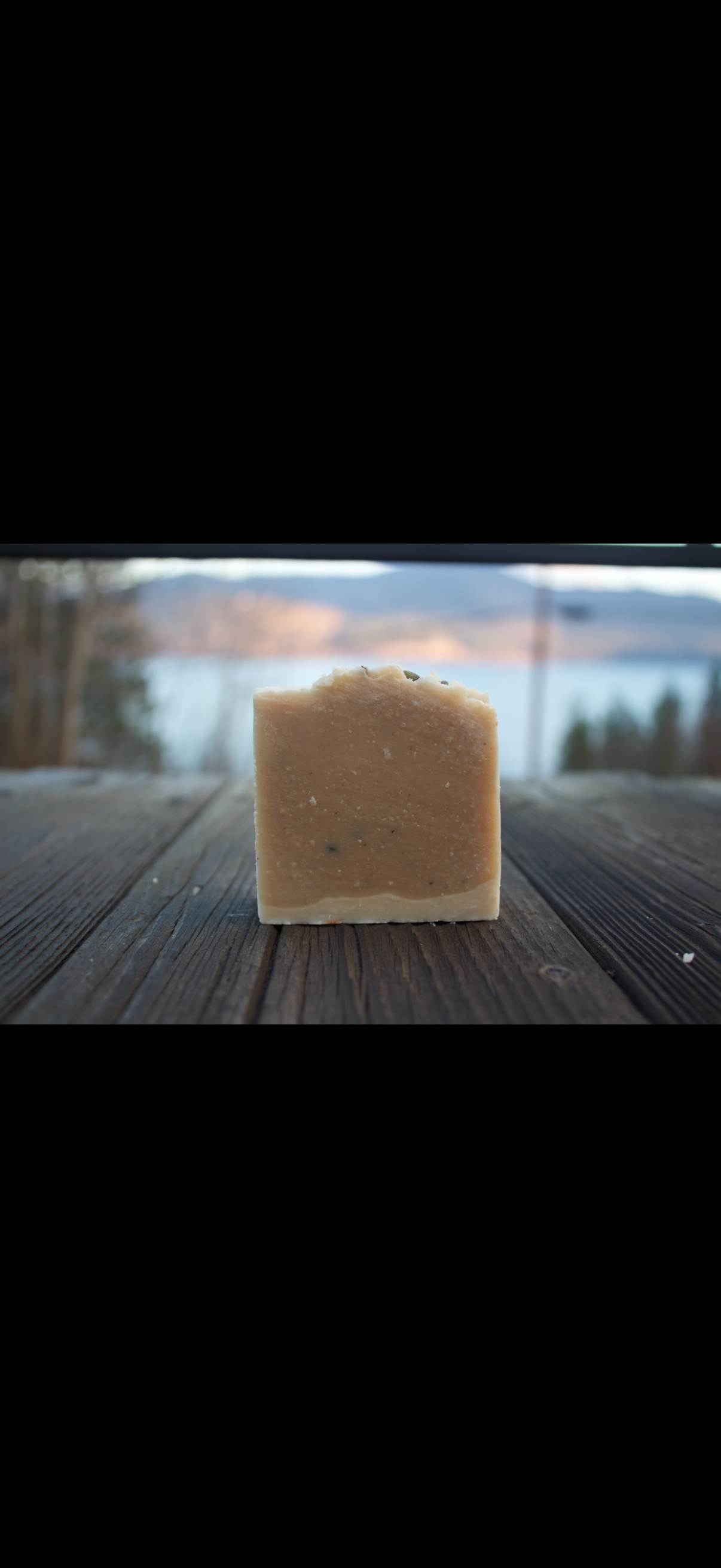 Bar of soap on a wooden surface with a scenic background