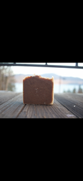 Block of soap on a wooden surface with a blurred natural background