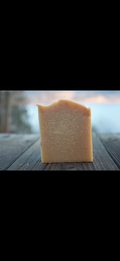 Bar of soap on a wooden surface with a blurred natural background