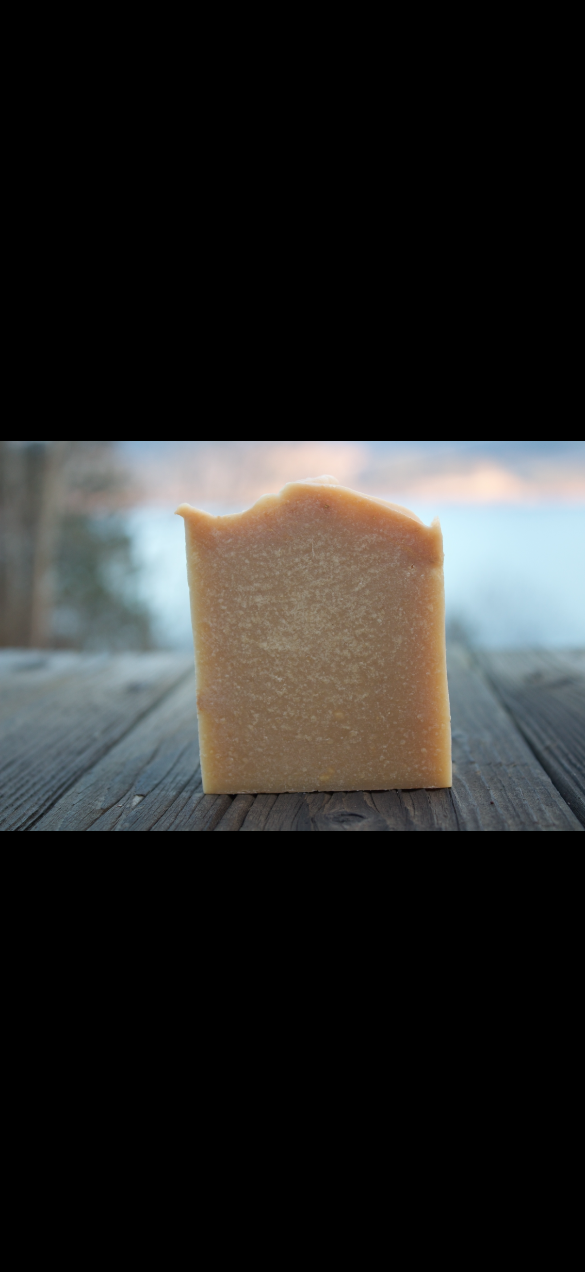 Bar of soap on a wooden surface with a blurred natural background